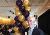 John Cady at the Staff Awards, standing in front of gold and purple balloons