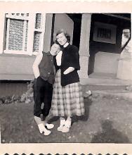 1950's photo of two women in front of a house, with faces blurred