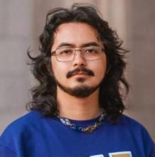 student with dark hair, wearing glasses and purple shirt