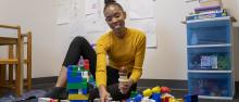 Deja Edwards on the floor with toys in the Social Cognitive Development Lab.