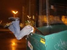 A man hanging over the side of a dumpster