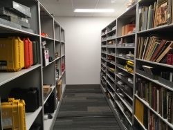 A hallway flanked by two open shelving units with books and objects on them