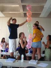 Students designed a leadership development activity in which groups competed to build the tallest tower with a set of materials: balloons, a box of straws, tape, and a paper bag (Ronnie Fouch holding the balloons)