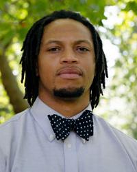 Dr. Logan, wearing a bowtie with a tree in the background