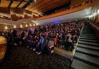 Students and family sit in an auditorium looking on as students who received their certificate walk back to their seats