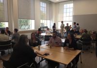Photo of Denny Hall 313, on April 26th featuring tables with students and consultants in discussion