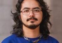 student with dark hair, wearing glasses and purple shirt