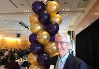 John Cady at the Staff Awards, standing in front of gold and purple balloons