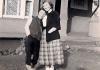 1950's photo of two women in front of a house, with faces blurred