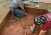 Two people excavating a shallow section at an archaeological site. 